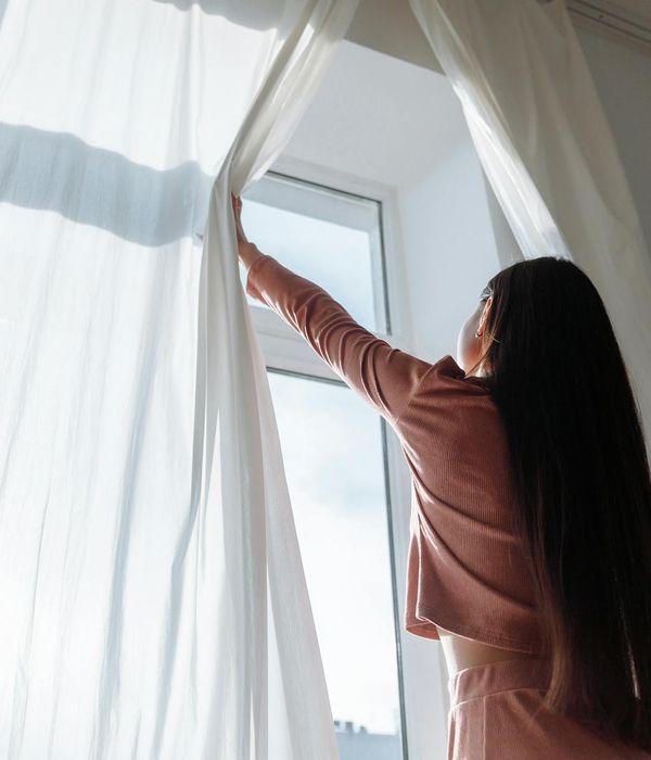 Woman performing a gentle stretching exercise in a bright, airy room with light blue accents.